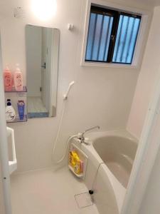 ein weißes Bad mit einer Badewanne und einem Spiegel in der Unterkunft 天下茶屋浪漫满屋 in Osaka