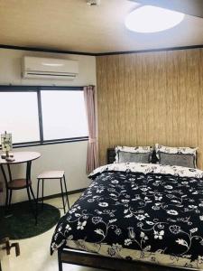 Schlafzimmer mit einem schwarzen und weißen Bett und einem Tisch in der Unterkunft 天下茶屋浪漫满屋 in Osaka