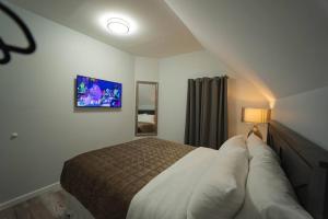 Modern, Luxury 2 Bedroom Apt in Prime Location في سكينيكتدي: غرفة نوم مع سرير وتلفزيون على الحائط