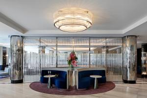 een lobby met een blauwe bank, 2 tafels en een kroonluchter bij The Royce in Melbourne