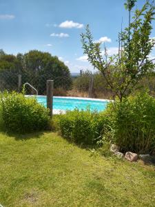 una piscina con valla y césped verde en Casa Entelequia en Las Compuertas