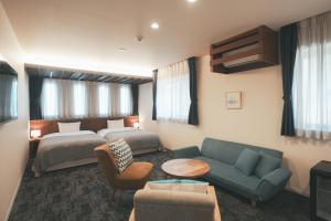 広島市にあるLAZULI Hiroshima Hotel and Loungeのベッドとソファ付きのホテルルーム