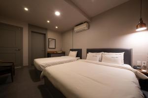 um quarto de hotel com duas camas com lençóis brancos em No25 Hotel Yeonsan em Busan