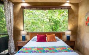 um quarto com uma cama e uma grande janela em Arbol Verde Villas em Ojochal