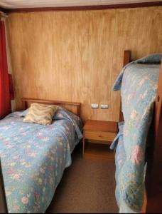 a small bedroom with two beds and a night stand at Cabaña con estacionamiento in Panguipulli
