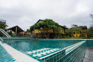 a swimming pool with lounge chairs in front of a house at Greenfield Ecostay in Phong Nha