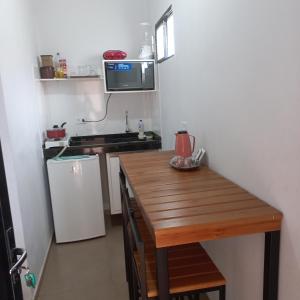 małą kuchnię z drewnianym stołem i kuchenką mikrofalową w obiekcie kitnet completa no Centro w mieście Carolina