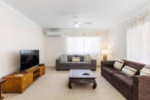 a living room with a couch and a tv at Charlesworth on Elizabeth in Coffs Harbour