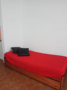 Una cama roja con dos almohadas negras. en ZEN BEACH en Santa Teresita