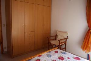 a bedroom with a bed and a chair and cabinets at Akrojali in Kómboi