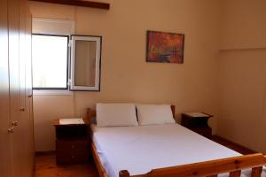 a bedroom with a white bed with a window at Anastassia EG in Koroni