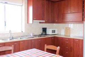 cocina con armarios de madera, mesa y microondas en Anastassia OG, en Koroni