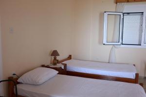 Dos camas en una habitación pequeña con ventana. en Anastassia OG, en Koroni
