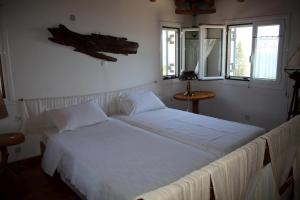 a bedroom with two beds with white sheets and windows at Alexia in Selinitsa