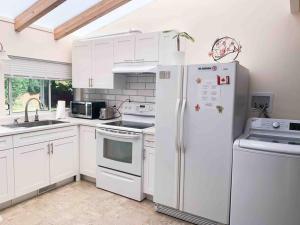 a kitchen with white cabinets and a white refrigerator at Separate access suite , separate kitchen, bathroom in Surrey