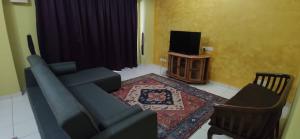 Al Irfan Homestay Tmn SgDua Utama في بترورث: غرفة معيشة بها أريكة زرقاء وتلفزيون