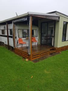 a mobile home with two chairs on a deck at Te Puru Holiday Park in Thames