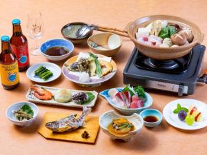 a table with plates of food and a pot on a stove at Sachinoyu Hotel Shiga Kogen in Yamanouchi
