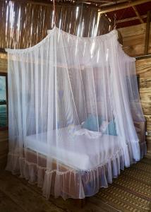 1 cama con dosel y cortinas blancas en una cabaña en Palmarío Hostal en Guachaca
