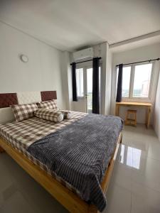 a bedroom with a large bed in a room with windows at Apartment Grand Sentraland Karawang Manage by Laguna Room in Karawang