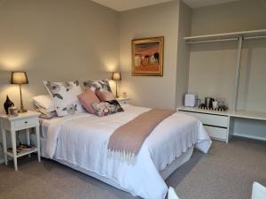 a bedroom with a large white bed with pillows at Omokoroa Golfers Retreat - B&B in Omokoroa