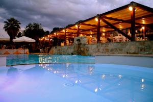 a swimming pool in front of a restaurant at night at Agriturismo Roccadia in Carlentini
