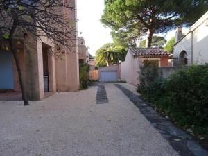 alejka między dwoma budynkami z drzewami i płotem w obiekcie Appartement Hyères : 2 pièces, jardin privé, proche plage et port, WIFI, parking - FR-1-335-161 w Hyères +7 zdjęć