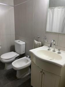 a white bathroom with a toilet and a sink at Casa Balcarce Mendoza in Guaymallen