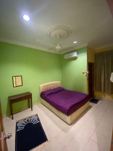 una camera con letto viola e pareti verdi di Qaseh Aida Guesthouse a Kampong Tanah Merah