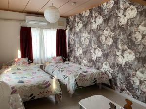 a bedroom with two beds and a floral wallpaper at B&B HOTTA in Sapporo