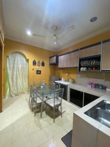 Qaseh Aida Guesthouse في Kampong Tanah Merah: مطبخ مع طاولة وكراسي في مطبخ