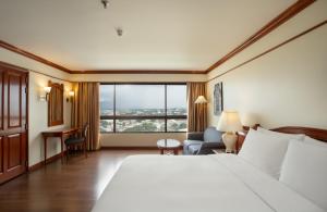 チェンマイにあるCentara Riverside Hotel Chiang Maiのベッドと大きな窓が備わるホテルルームです。