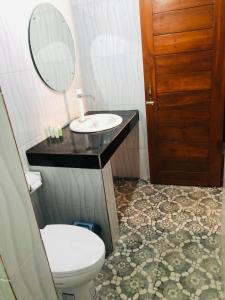 bagno con servizi igienici, lavandino e specchio di Padangbai Beach inn a Padangbai