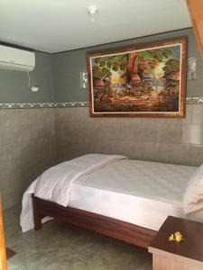 een slaapkamer met een bed met een schilderij aan de muur bij Raditya Homestay in Mambat