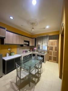 Qaseh Aida Guesthouse في Kampong Tanah Merah: مطبخ مع طاولة زجاجية وكراسي فيه