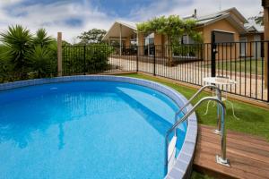a swimming pool with a fence and a house at Mhara Downs Country Escape in Foster