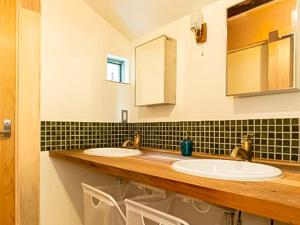 two sinks in a bathroom with black and white tiles at Trawl Guesthouseトロールゲストハウス in Koshigoe