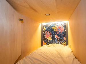 um quarto com uma cama com um quadro na parede em Trawl Guesthouseトロールゲストハウス em Koshigoe