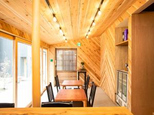 Habitación con techo de madera, mesa y sillas. en Trawl Guesthouseトロールゲストハウス, en Koshigoe