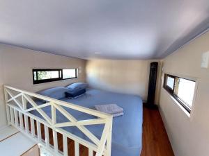 a bedroom with a blue bed and two windows at Tiny house with extended camping area for large groups in Puerto Viejo