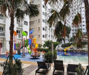 a playground in the middle of a building with palm trees at Shore Residences in Manila