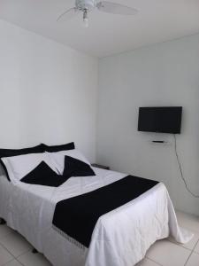 1 dormitorio con 1 cama y TV en la pared en Casa com piscina no Campeche en Florianópolis