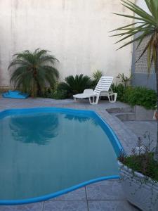 una piscina azul con una silla y un banco en Casa com piscina no Campeche, en Florianópolis