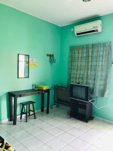 Zimmer mit einem Schreibtisch, einem TV und einem Tisch in der Unterkunft Chalet Sri Damai in Kampong Pengkalan Maras