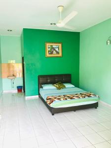 um quarto com uma cama numa parede verde em Chalet Sri Damai em Kampong Pengkalan Maras
