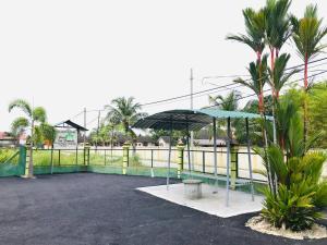 um parque de estacionamento com um guarda-sol azul e palmeiras em Chalet Sri Damai em Kampong Pengkalan Maras