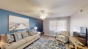 a living room with a couch and a ceiling fan at TURTLE'S NEST DUPLEX Duplex in Jekyll Island