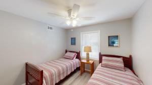 a bedroom with two beds and a ceiling fan at TURTLE'S NEST DUPLEX Duplex in Jekyll Island
