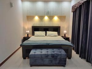 sypialnia z dużym łóżkiem i niebieską otomaną w obiekcie Fully Serviced Holiday Home Near Lahore Ring Road w mieście Lahaur