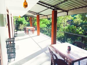 a porch with a table and chairs and a view of the forest at Ella South Star in Ella